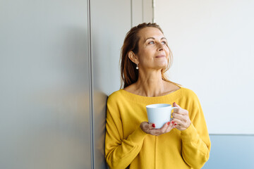 Middle-aged woman standing daydreaming or reliving memories