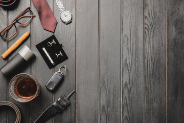 Stylish male accessories and glass of whiskey on dark wooden background