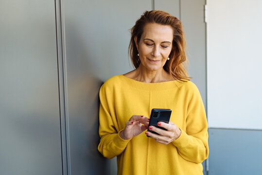 Attractive stylish middle-aged woman browsing on a mobile phone