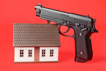 Model of house and gun on color background. Concept of hostage