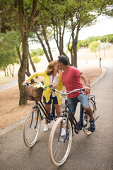 Portrait of happy mature bicyclists kissing in park. Senior lovers dating and riding bikes. Active seniors and mature love concept