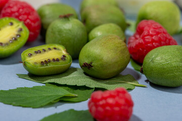 Fruit of actinidia arguta, kiwi berry fruits, raspberries and mint leaves close-up.