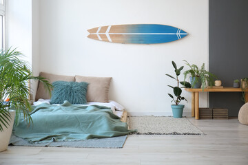 Interior of modern stylish bedroom with surfboard hanging on wall