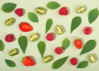 Fruit of actinidia arguta, kiwi berry fruits, raspberries, strawberries and mint leaves, on green background.