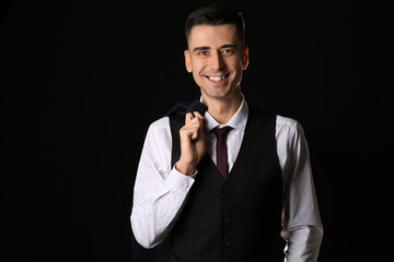 Handsome young man in stylish formal suit on dark background