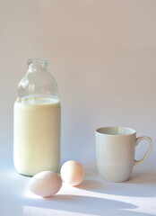Bottle with milk, coffee cup and eggs on white background