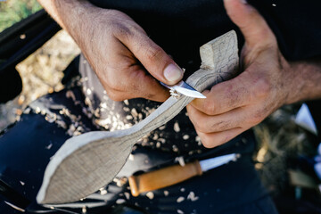 Close up of man carving branch with knife in nature