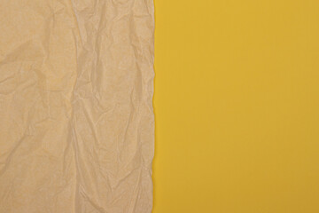 Beige old wrinkled creased paper sheet on yellow color background. Top view, copy space for text