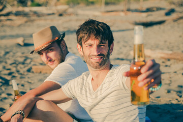 Portrait of friends having a rest on the beach drinking beer. Cheerful young people spending nice...