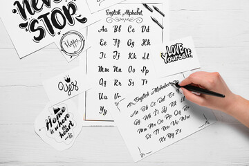 Woman writing alphabet on white wooden background