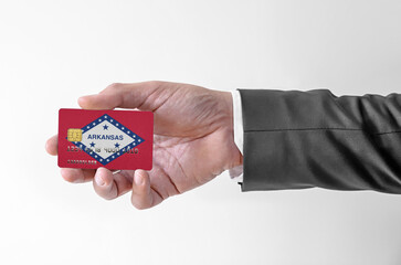 Bank credit plastic card with flag of USA state Arkansas holding man in elegant suit