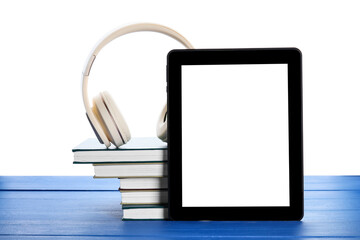 Modern headphones, tablet computer and books on color wooden table against white background