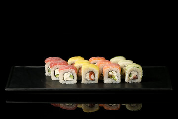 Plate with set of tasty sushi rolls on dark background
