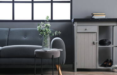 Glass vase with eucalyptus near wall in interior of stylish living room