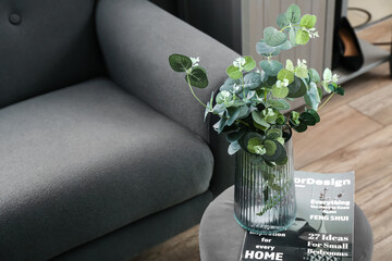 Stylish chair with glass vase of plant and magazine in modern living room
