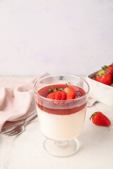Glass with tasty homemade strawberry panna cotta on light background