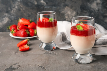 Tasty panna cotta with strawberry and mint in glasses on grunge background