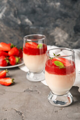 Delicious panna cotta with strawberry and mint in glasses on grunge background