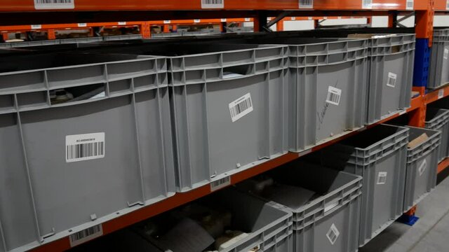 Large gray plastic boxes on storage racks in manufacturing
