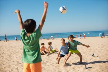 Boys fighting for ball when playing football. Excited preteen friends playing soccer on beach....