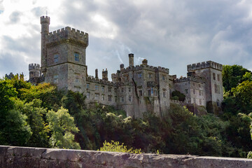old lismore castle in waterford, ireland with cloudy sky and trees all around - obrazy, fototapety, plakaty