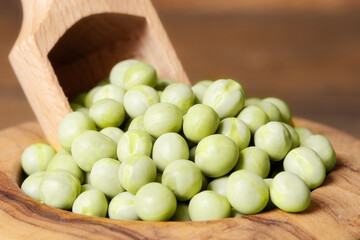 Closeup of peas in a bowl with a scoop.Dried green peas in a wooden bowl on wooden background .