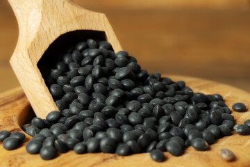 Closeup of beluga lentilsi n a bowl with a scoop. Beluga lentils in a wooden bowl on wooden background.