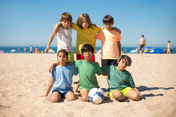 Portrait of serious preteen boy friends on beach. Group of multiethnic kids embracing and looking at camera at seaside. Summer vacation, friendship concept