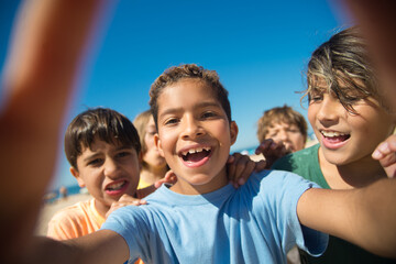 Selfie of cheerful multiethnic preteen boy friends. Portrait of happy kids on beach. Summer vacation and friendship concept