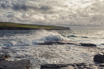 Powerful ocean waves hit rough stone coast. Doolin, county Clare, Ireland. Dark dramatic light and cloudy sky. Irish landscape. Power of nature concept. Dramatic image
