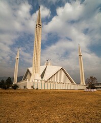 Faisal Mosque Islamabad, Pakistan views with brown grass in foreground on a cloudy day. A clear shot of King Faisal Mosque in Islamabad, Pakistan.