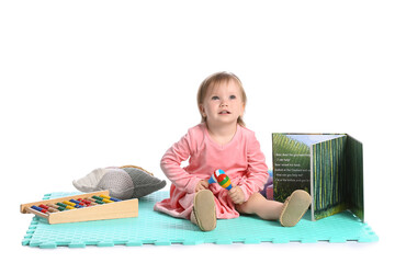 Cute baby girl with toys and book on white background