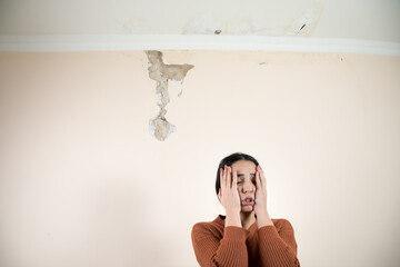 damaged ceiling with sad woman in home