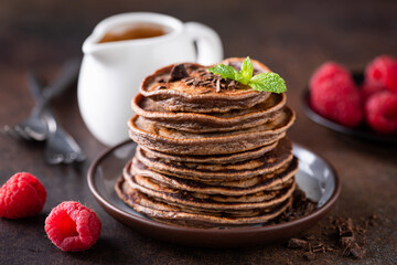 Stack of chocolate pancakes served with raspberries, closeup view