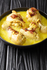 Opor ayam chicken cooked in coconut milk with spices close up in the bowl on the table. Vertical