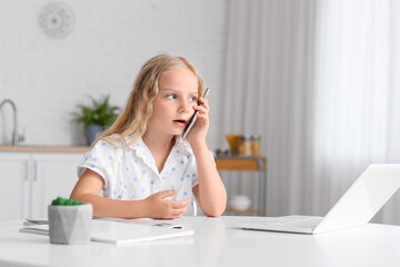 Cute little girl talking by phone at home