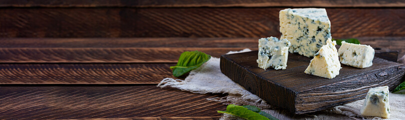 Sliced blue cheese on wooden background. Tasty dorblue on cutting board