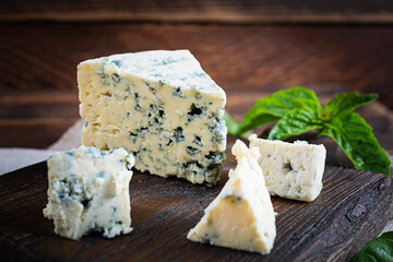 Sliced blue cheese on wooden background. Tasty dorblue on cutting board