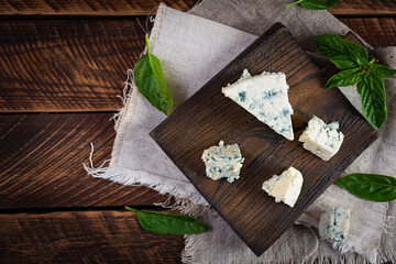 Naklejka na ściany i meble Sliced blue cheese on wooden background. Tasty dorblue on cutting board