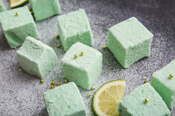 Tasty sweet marshmallows and lime on grunge background