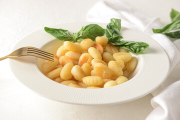 Plate with tasty gnocchi on light background