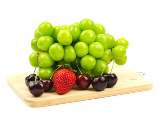 Shine Muscat grape, strawberry and cherry on cutting board isolated on a white background. .