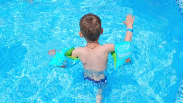 Summer vacation concept. Kid splashing on summer pool. Excited toddler boy splashing water. Happy childhood. Adorable boy playing and splashing in swimming pool. Cute child playing in swimming pool.