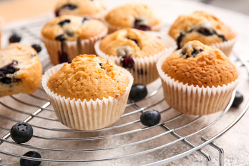 Grid with tasty blueberry muffins on table, closeup