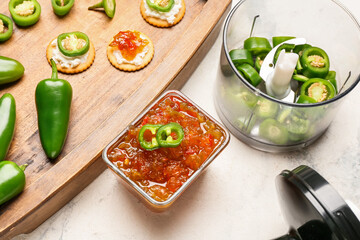 Bowl with delicious jalapeno pepper jam on light table, closeup