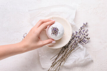 Female hand with lavender bath bomb on light background