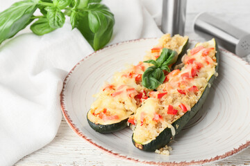 Plate with quinoa stuffed zucchini boats on light wooden background