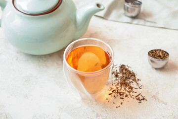Obraz na płótnie Canvas Glass of tasty hojicha green tea and pot on light background