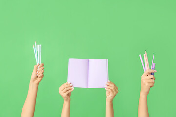 Many different hands with school supplies on green background