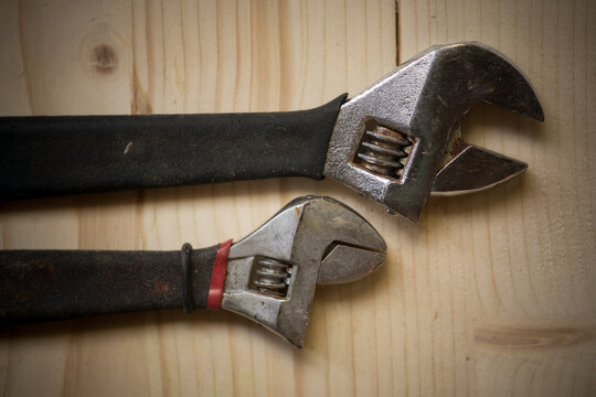 Two adjustable wrenches on a wooden background
